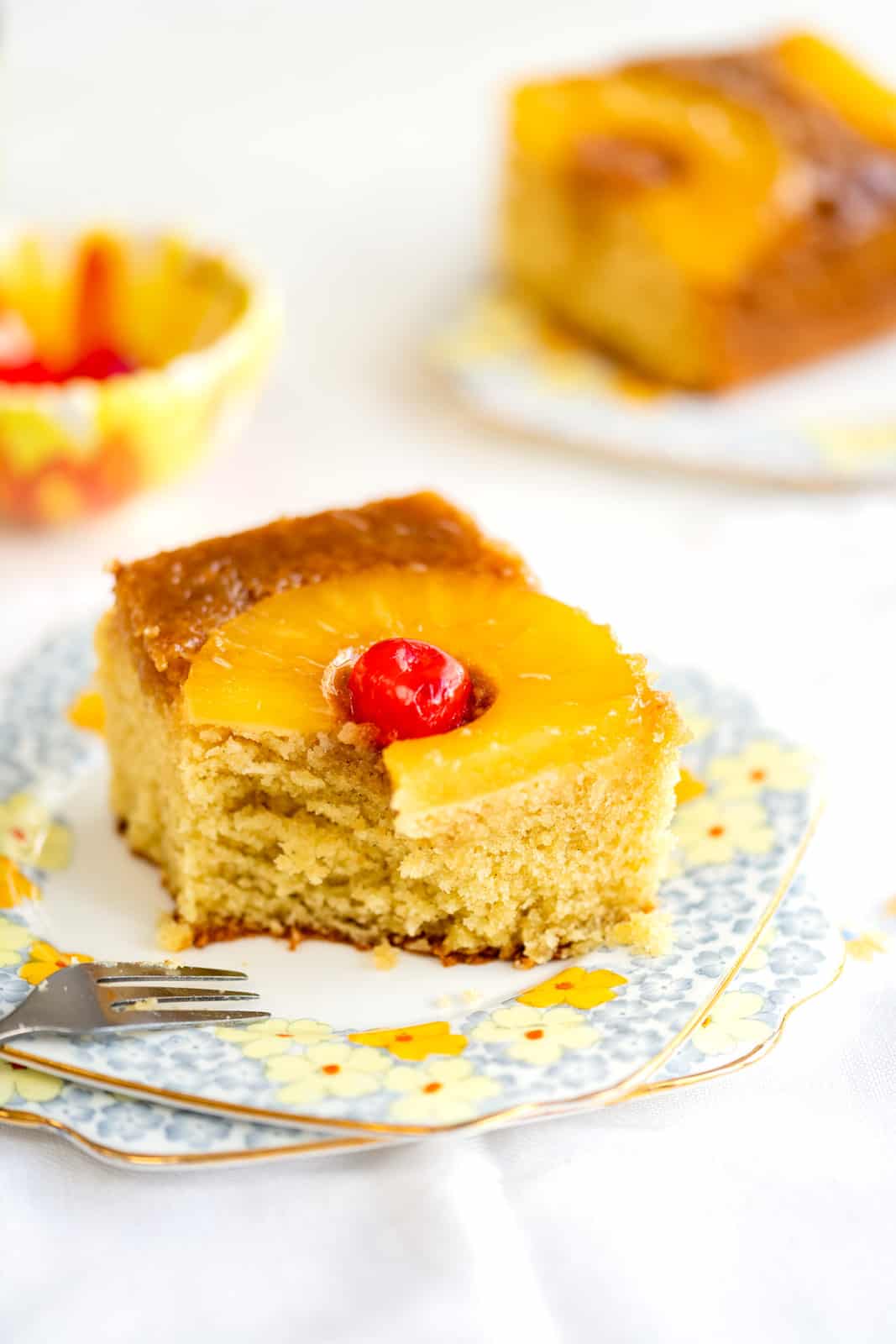 Slice of Pineapple Upside Down Cake on a floral plate with bite taken out