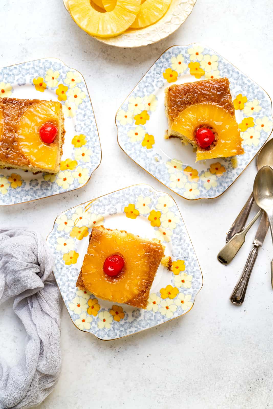 three slices over pineapple cake on floral vintage plates shown overhead
