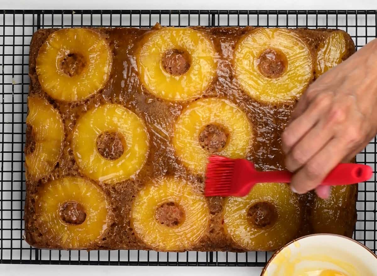 brushing pineapple upside down cake with warm apricot jam