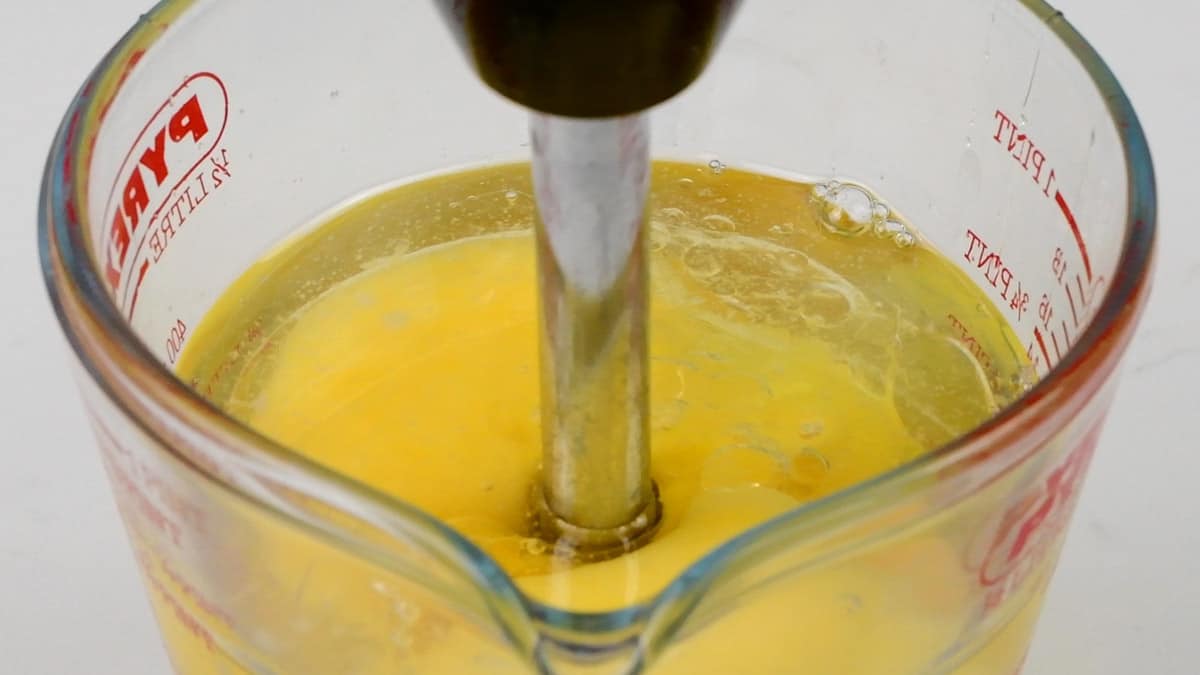 blending banana, coconut oil and eggs in a measuring jug