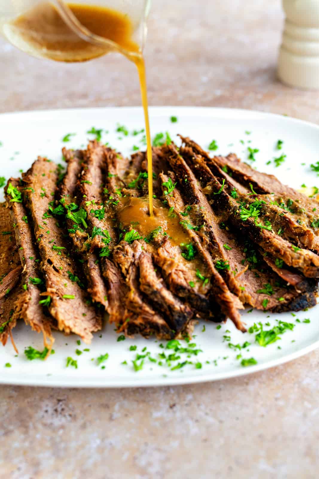 sliced beef brisket arranged on a platter and drizzled with gravy