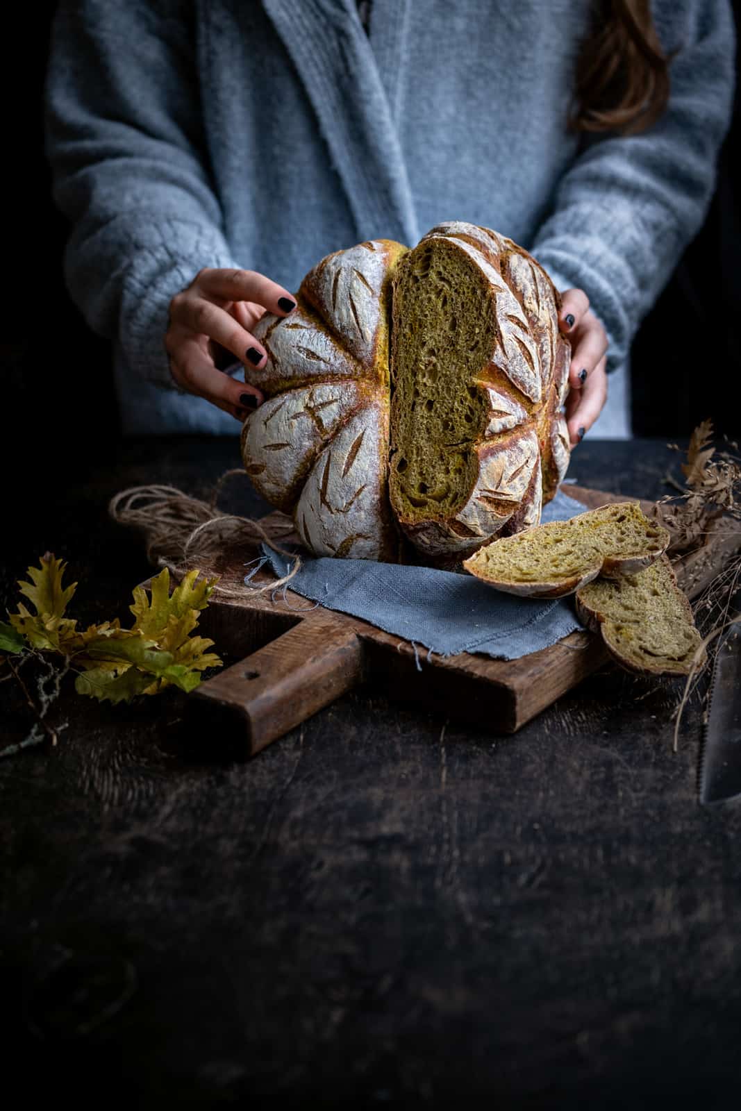Woman holding sourdough pumpkin bread sliced in half to show the interior of the loaf
