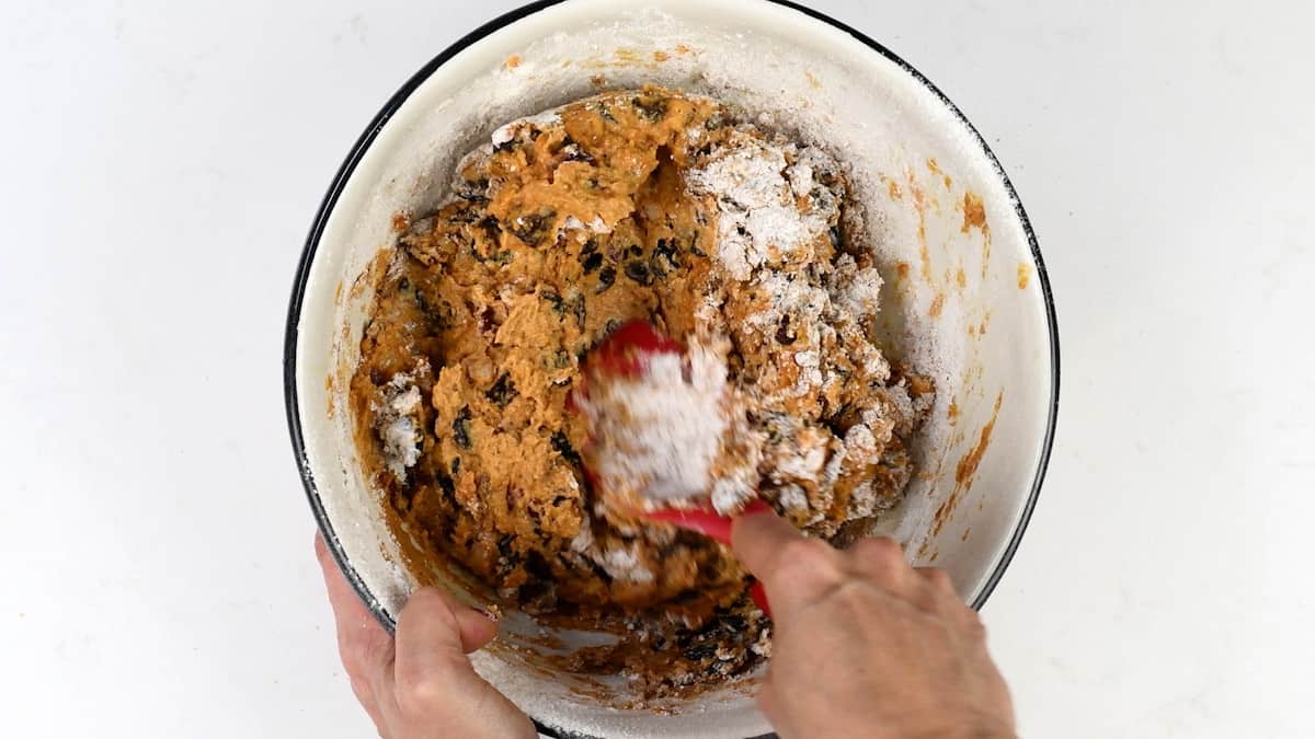 folding flour into fruit cake batter in a mixing bowl