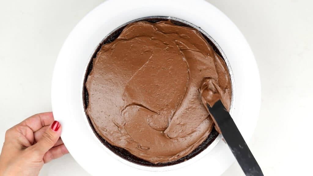 Spreading chocolate frosting over chocolate sponge cake