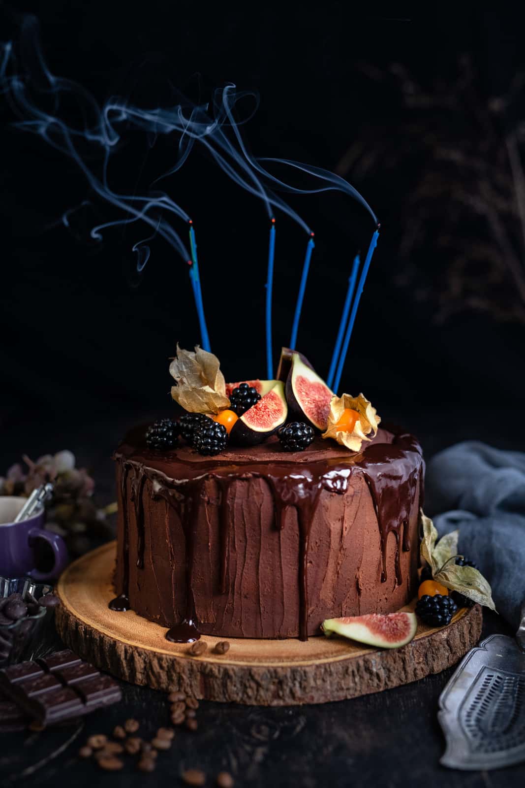 Moist chocolate cake, decorated with chocolate ganache drip and fruit with birthday candles blown out