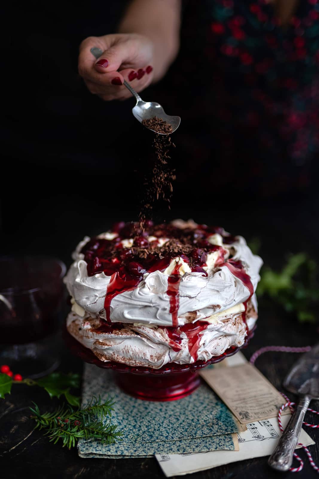 Layered Black Forest Pavlova on a small cake stand sprinkled with chocolate curls