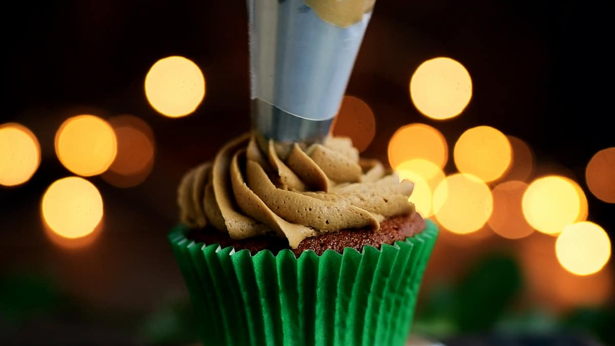 piping frosting over gingerbread cupcakes