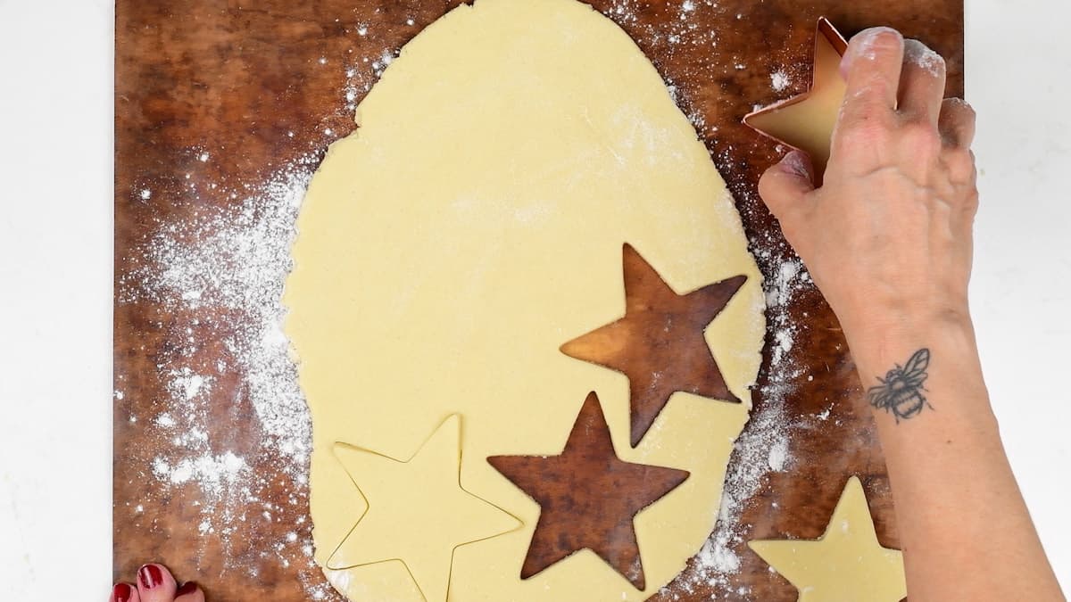 cutting out Christmas sugar cookies with a star shaped cookie cutter