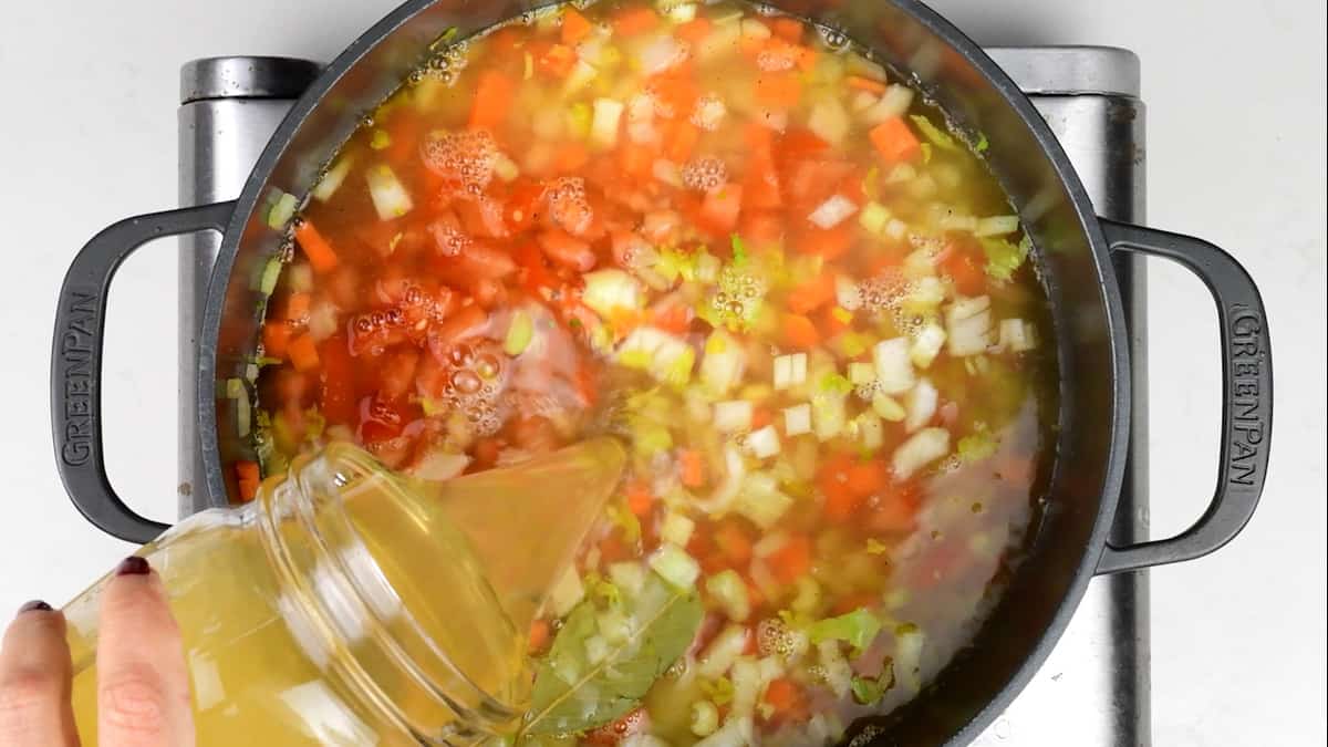 adding chicken stock to soup base in a pot