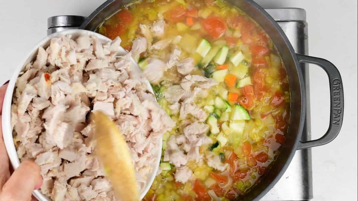 adding leftover turkey to soup simmering a in a pot