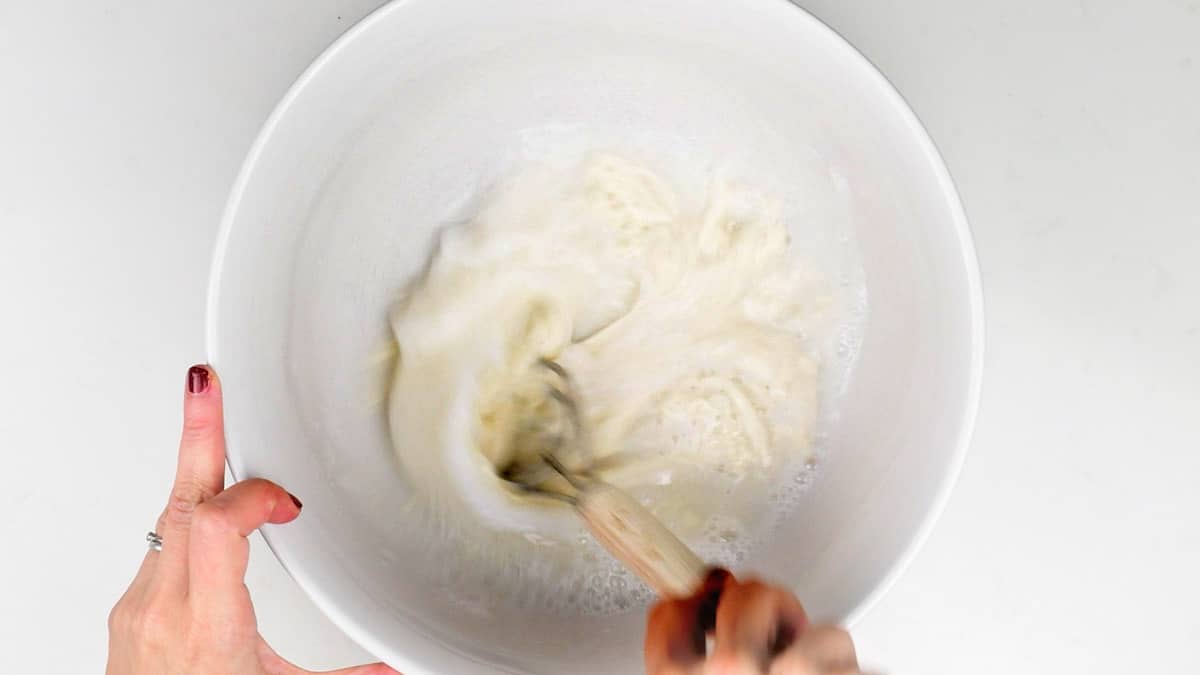 Stirring sourdough starter and water in a mixing bowl