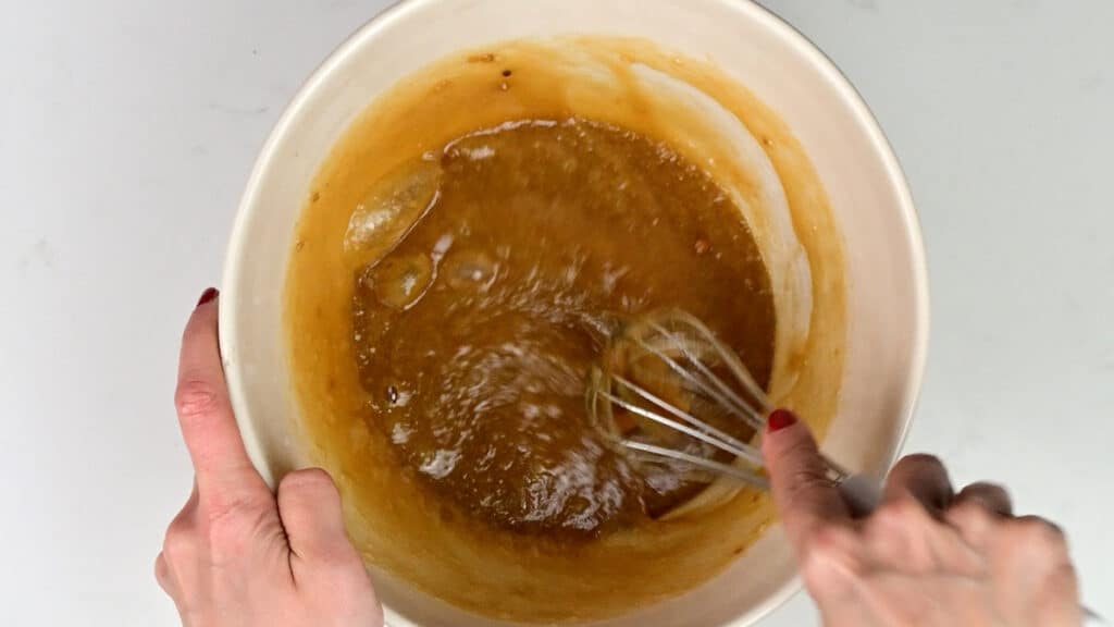 Beating eggs and sugar into brownie batter in a bowl