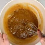Beating eggs and sugar into brownie batter in a bowl