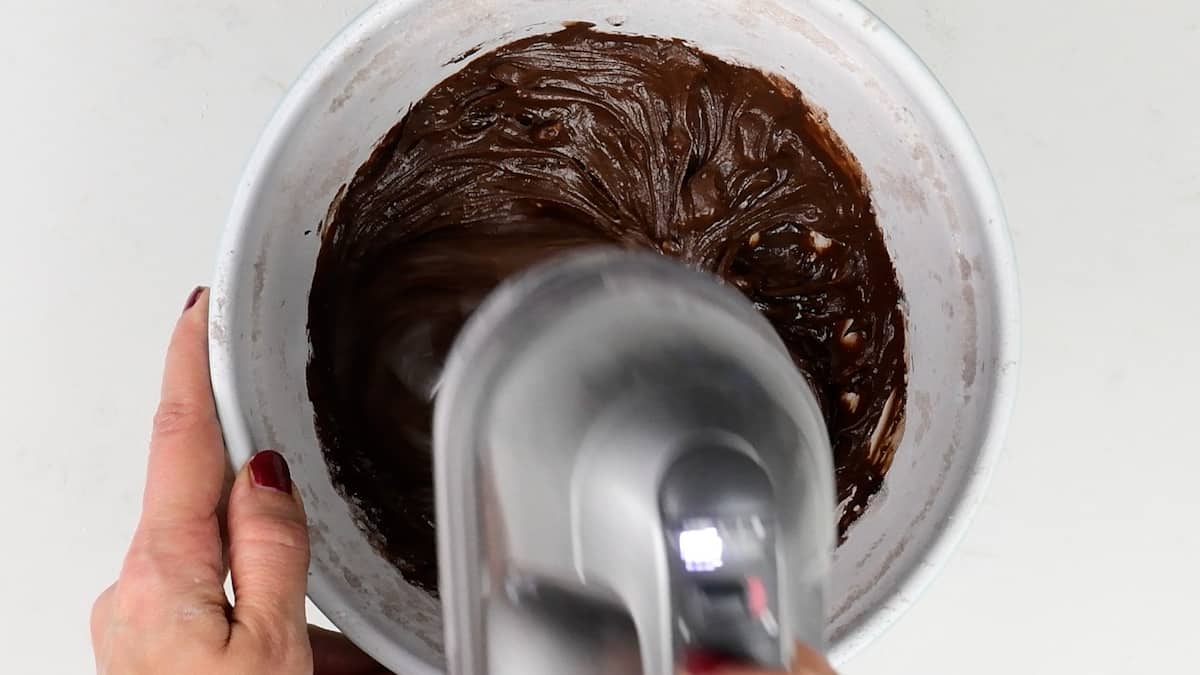 making chocolate frosting in a bowl with a hand mixer