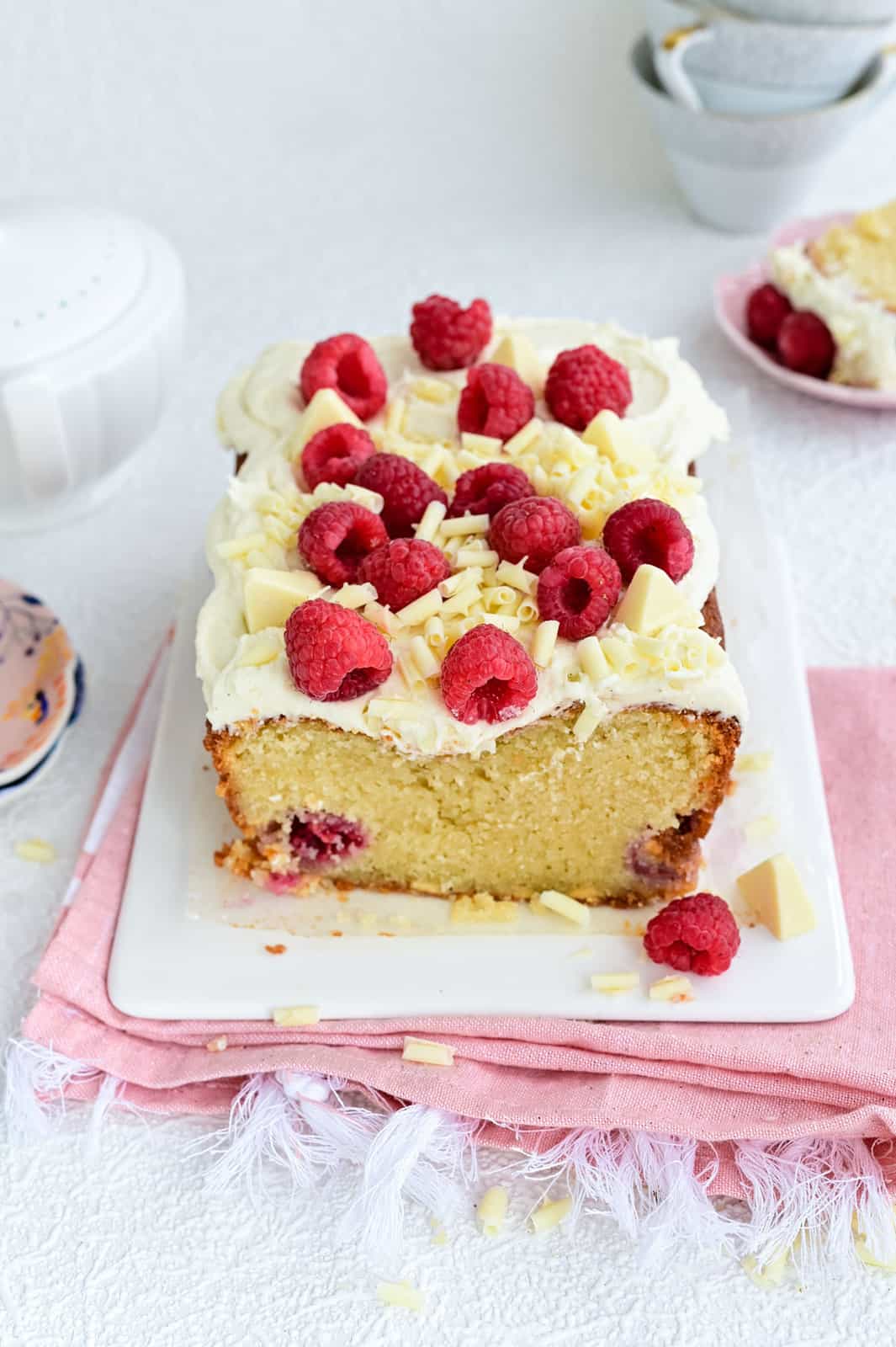 White Chocolate Raspberry loaf cake topped with buttercream and fresh raspberries
