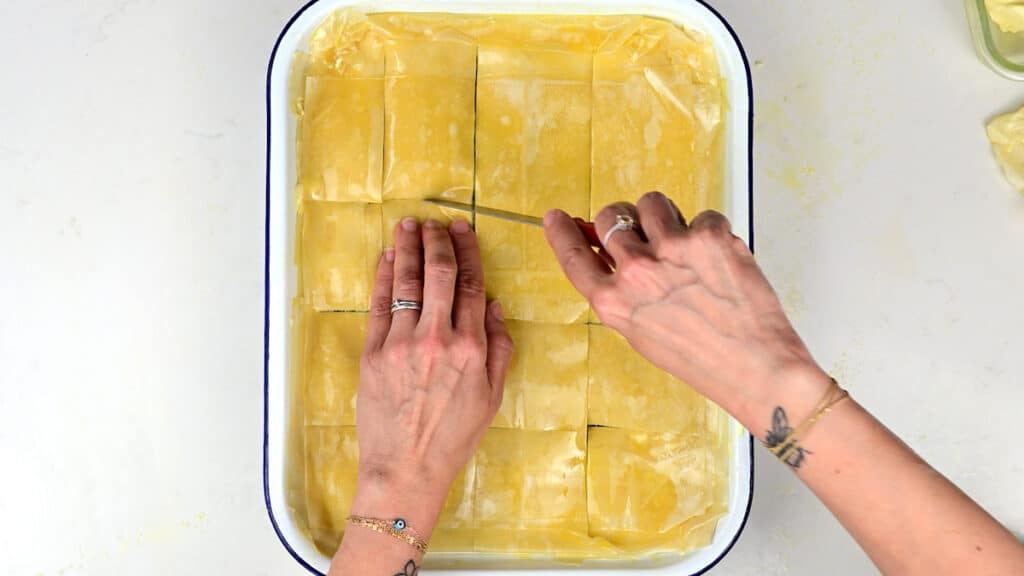 scoring the filo pastry covering spinach pie before baking