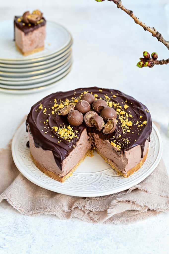 No Bake Baileys Cheesecake topped with chocolate and truffles with big slice cut out