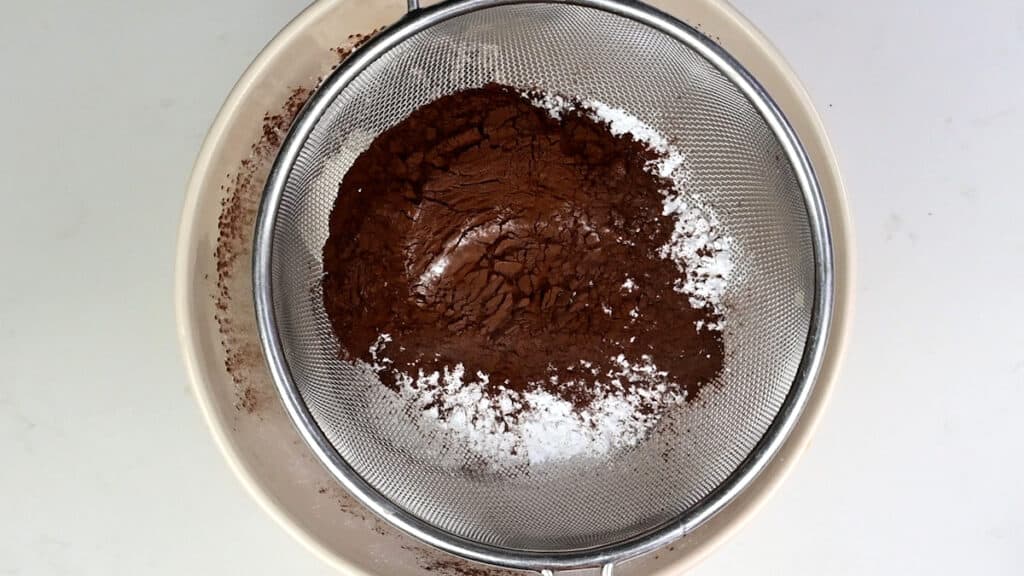sifting icing sugar and cocoa powder into bowl