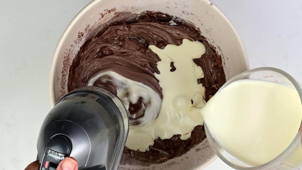 Adding cream to cheesecake filling in a bowl