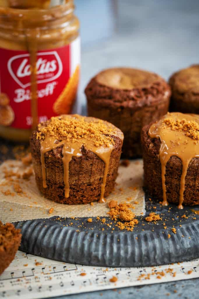 Lotus Biscoff muffins on a tray drizzled with cookie butter and biscuit crumbs