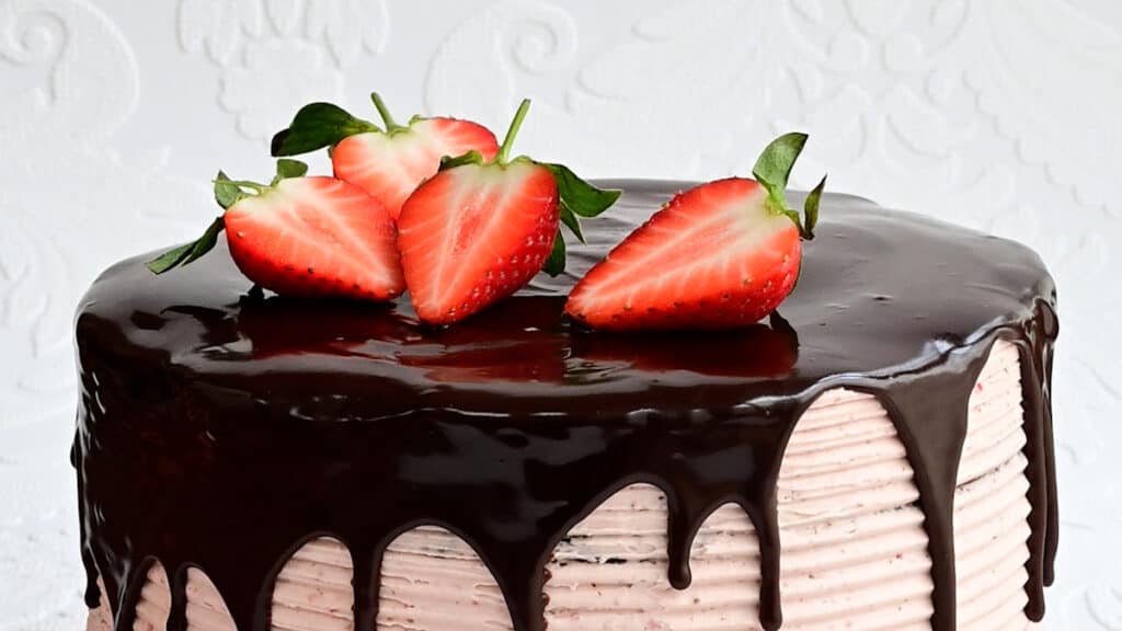 Topping chocolate strawberry cake with sliced fresh strawberries