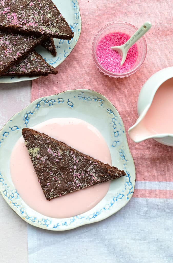 Overhead view of slice of chocolate concrete cake served with pink custard