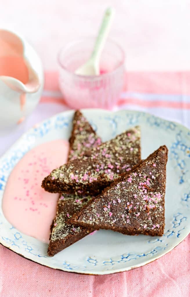Chocolate concrete cake cut into triangles and served with pink custard
