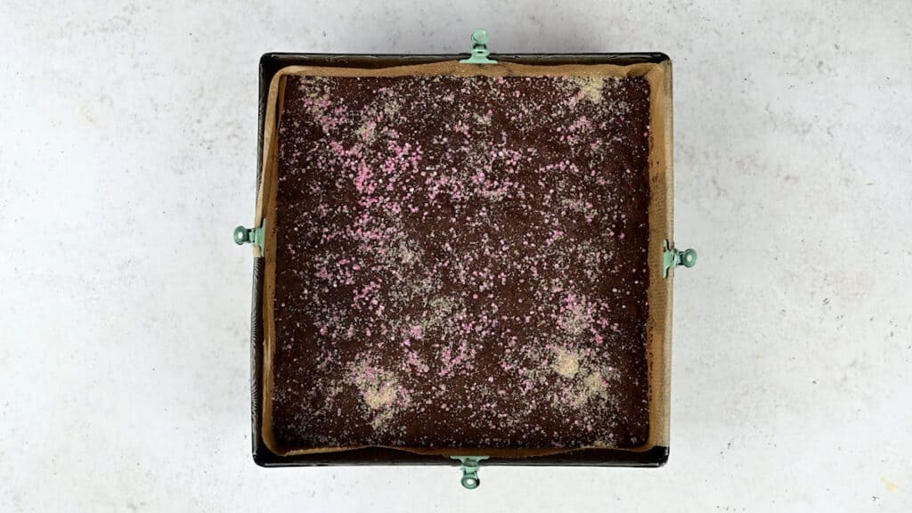 Chocolate crunch cake in square baking tin sprinkled with granulated sugar