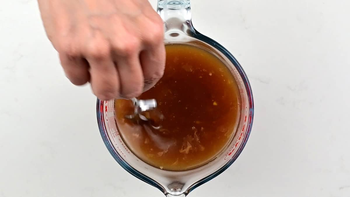 Stirring beef broth, mustard, Worcestershire sauce, tomato paste in a measuring jug