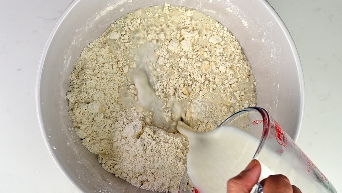 Pouring soured milk into flour in a mixing bowl