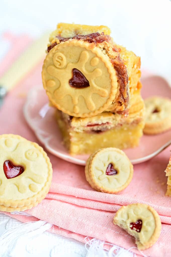 Jammie Dodger topped blondie squares stacked on a pink plate 