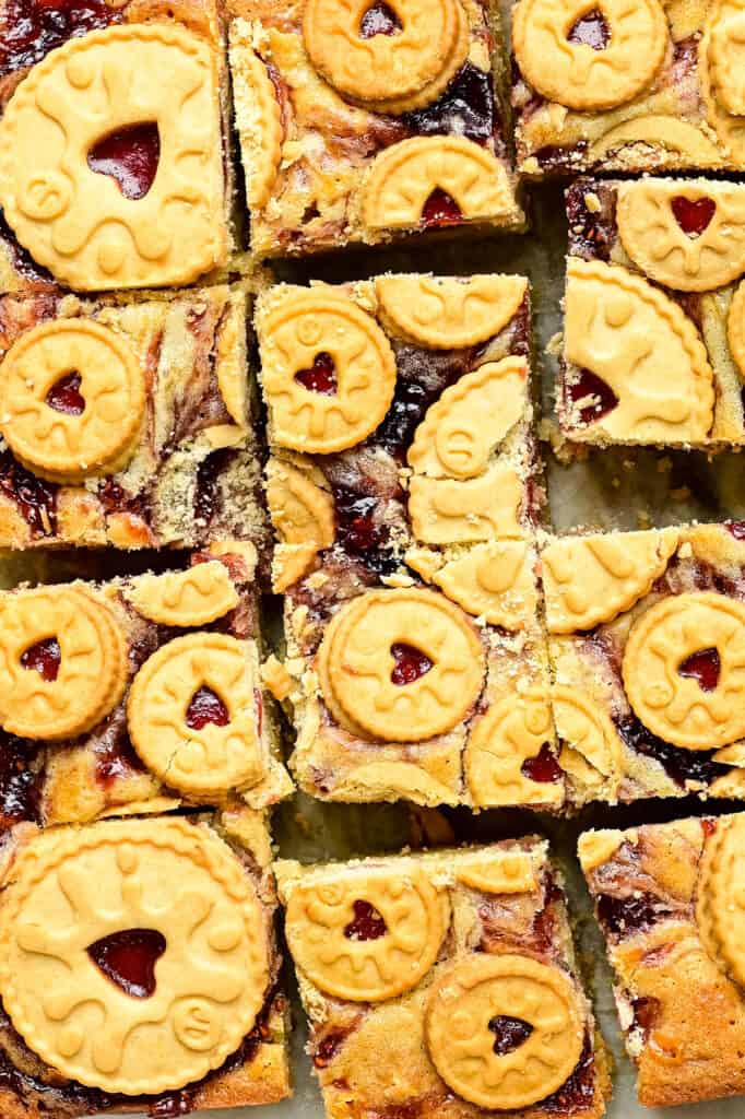 Close up on Delicious Jammie Dodger Blondies –  gooey white chocolate blondies swirled with raspberry jam and topped with Jammie Dodgers biscuits