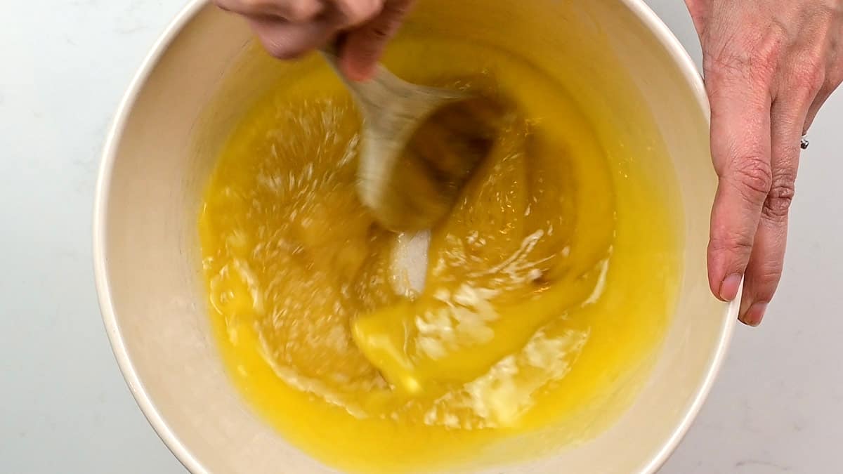 Stirring melted butter and sugar in a mixing bowl