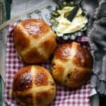 Three sourdough hot cross buns with butter on the side