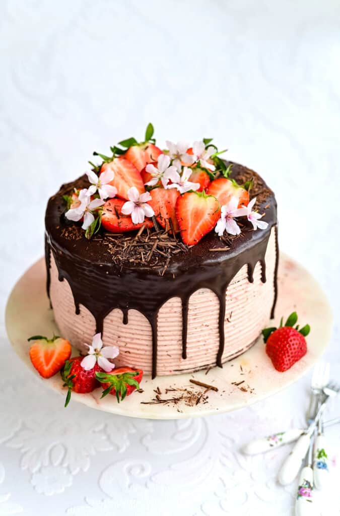 Chocolate strawberry cake decorated with fresh strawberries, chocolate shavings and fresh flowers