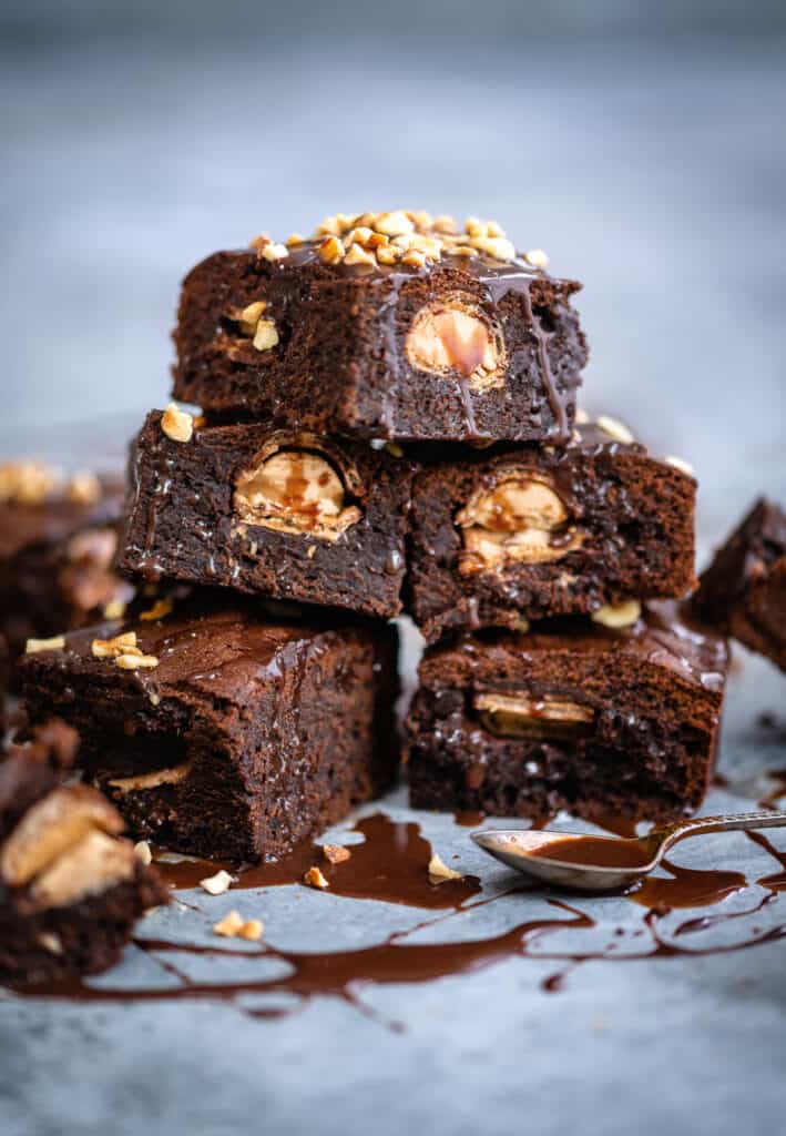 Stack of Kinder Bueno brownies drizzled with hazelnut spread and topped with chopped hazelnuts