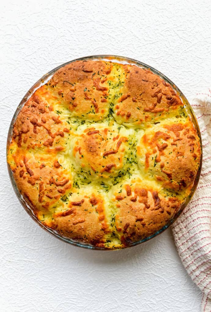 Fluffy dinner rolls with cheese and herbs in a round glass pyrex dish