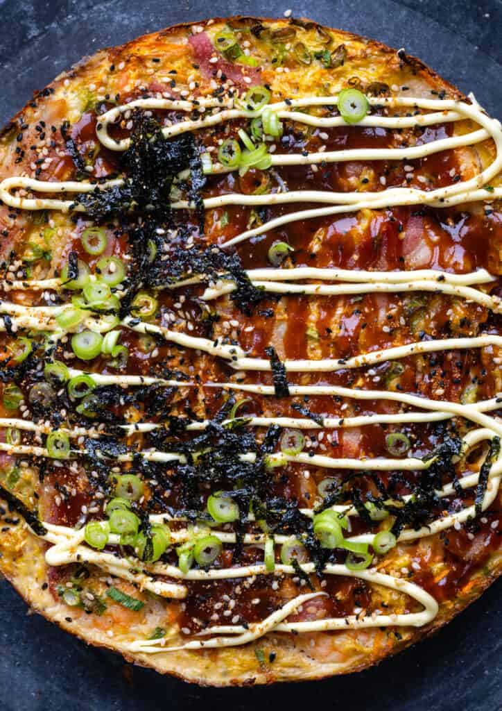 Homemade Okonomiyaki pancake topped with Kewpie mayonnaise, Okonomi sauce, nori and spring onions