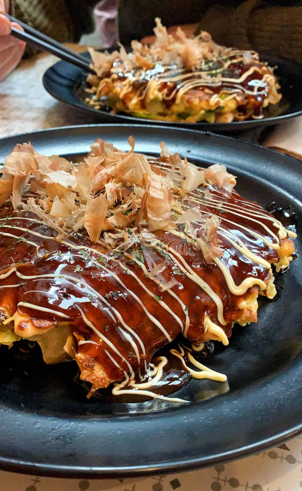 Okonomiyaki pancake served with bonito flakes, okonomi sauce and mayonnaise
