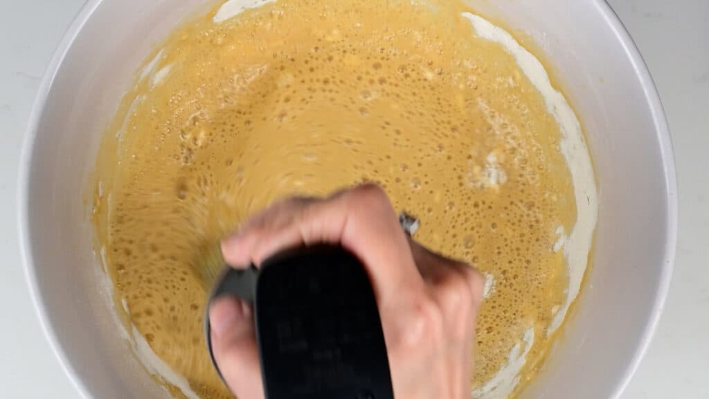 using an immersion blender to blitz pancake batter in a bowl