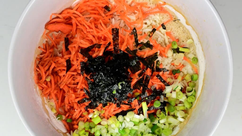 shredded carrot, cabbage, spring onions and seaweed in a mixing bowl