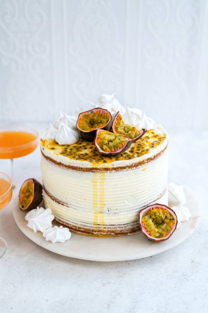 Passion fruit cake on a marble plate decorated with passion fruit and meringue cookies