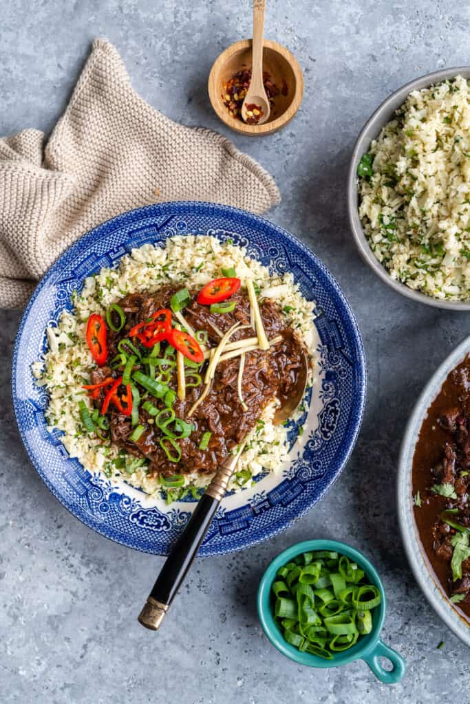 Soy braised shin of beef over cauliflower rice garnished with chillies and spring onions