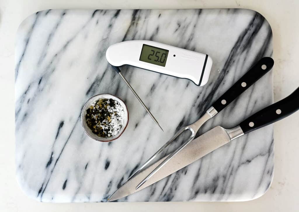 Digital thermometer, carving set and seasoning on a marble board