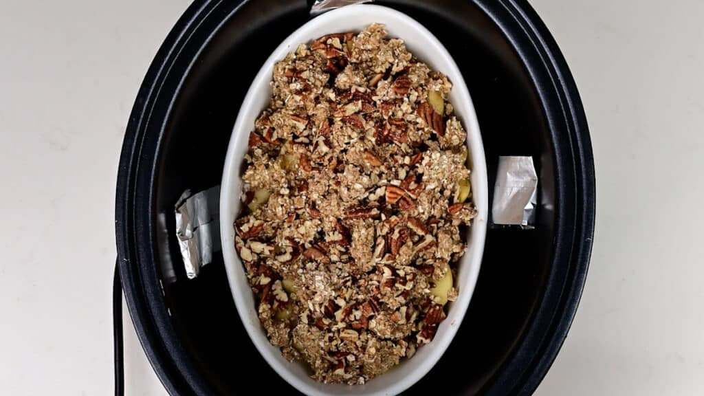 Ceramic dish with apple crumble in a slow cooker
