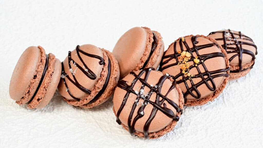 six chocolate macarons on a white background