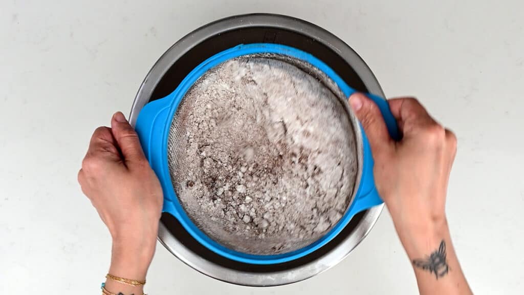 sifting almond flour, icing sugar and cocoa powder into a bowl
