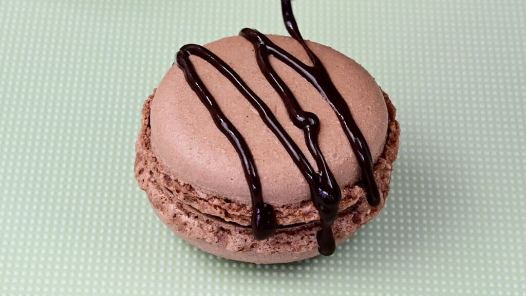 drizzling macarons with chocolate to decorate the shells