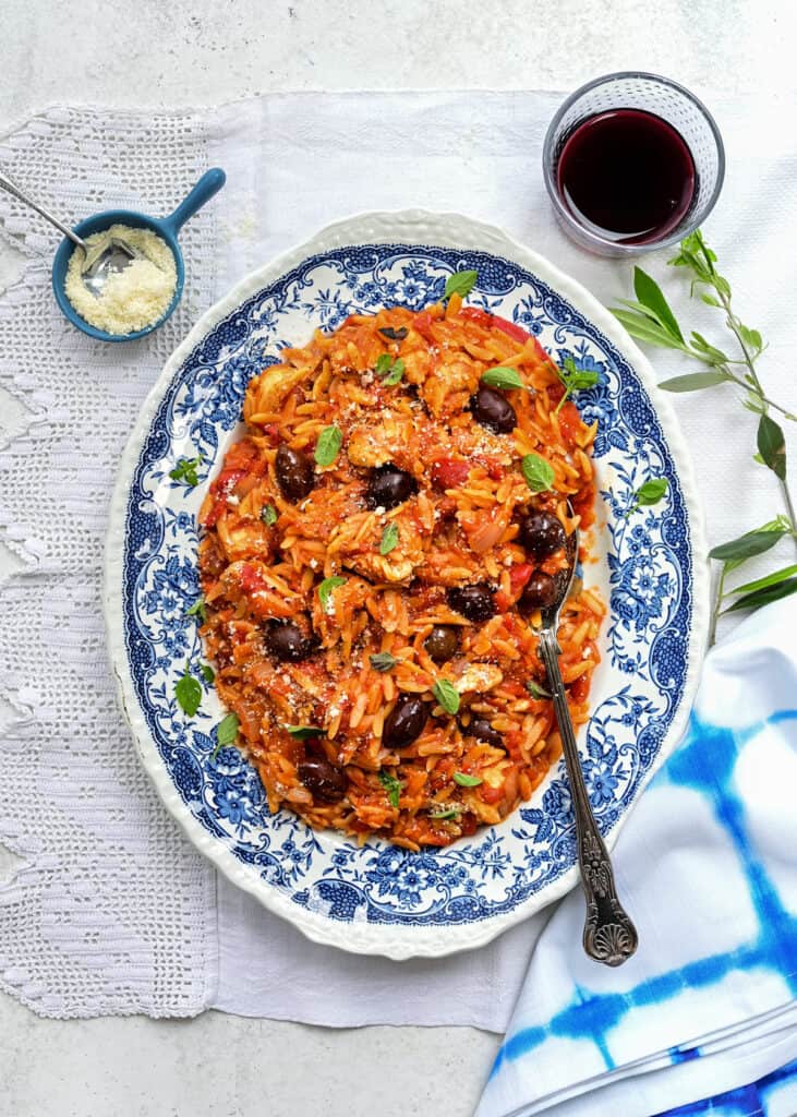 Greek chicken and orzo pasta on a blue platter