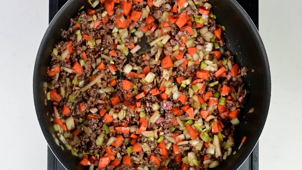 cooking steak mince, onion, carrot and celery in a pan